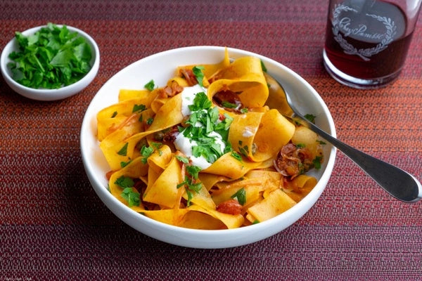 A bowl of pappardelle pasta with rose harissa olives capers