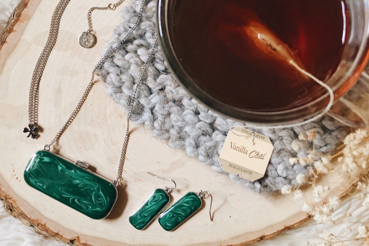 Cup of tea next to homemade emerald jewelry